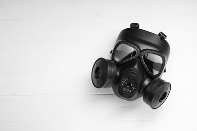Photo of One gas mask on white wooden background, top view. Space for text