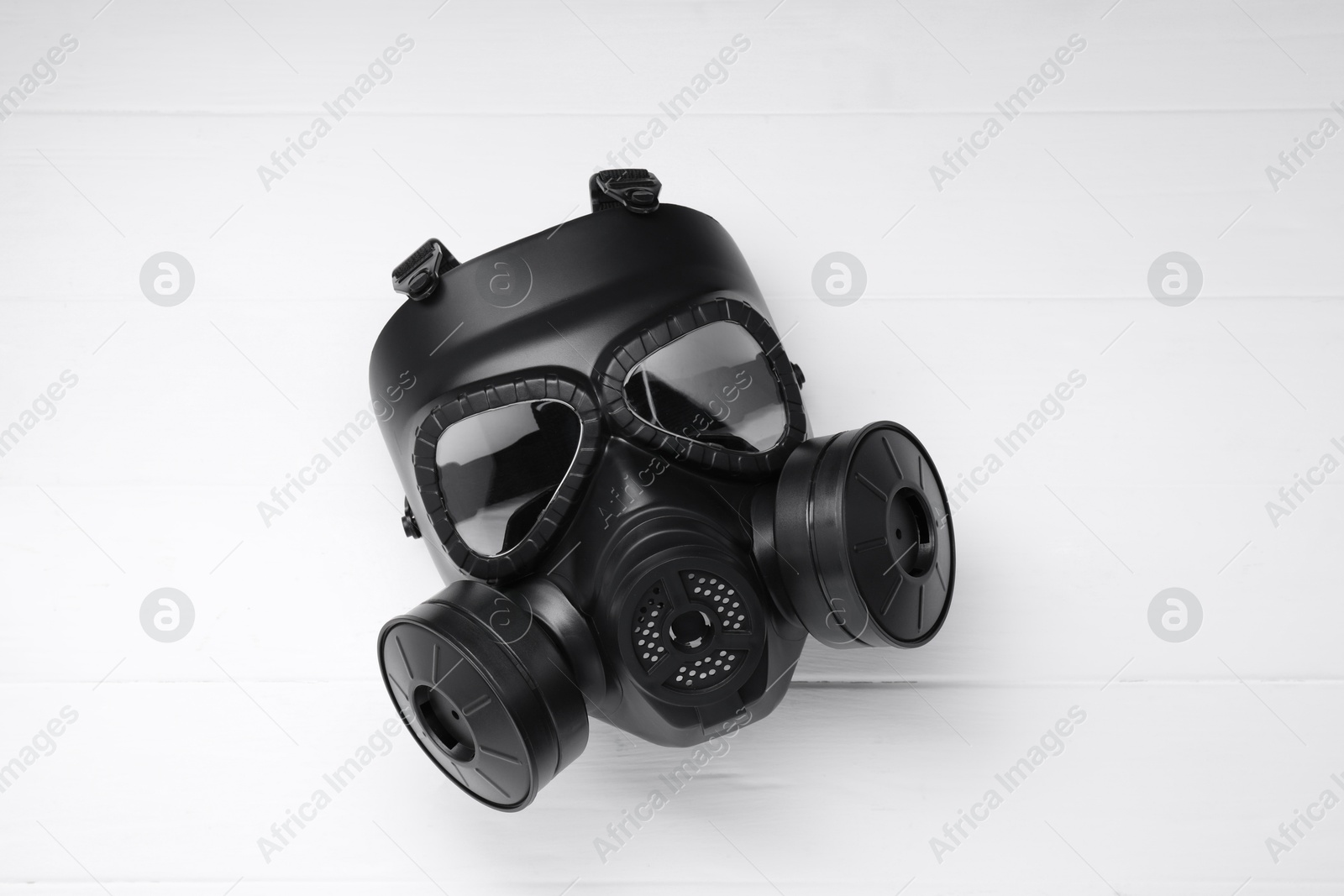 Photo of One gas mask on white wooden background, top view