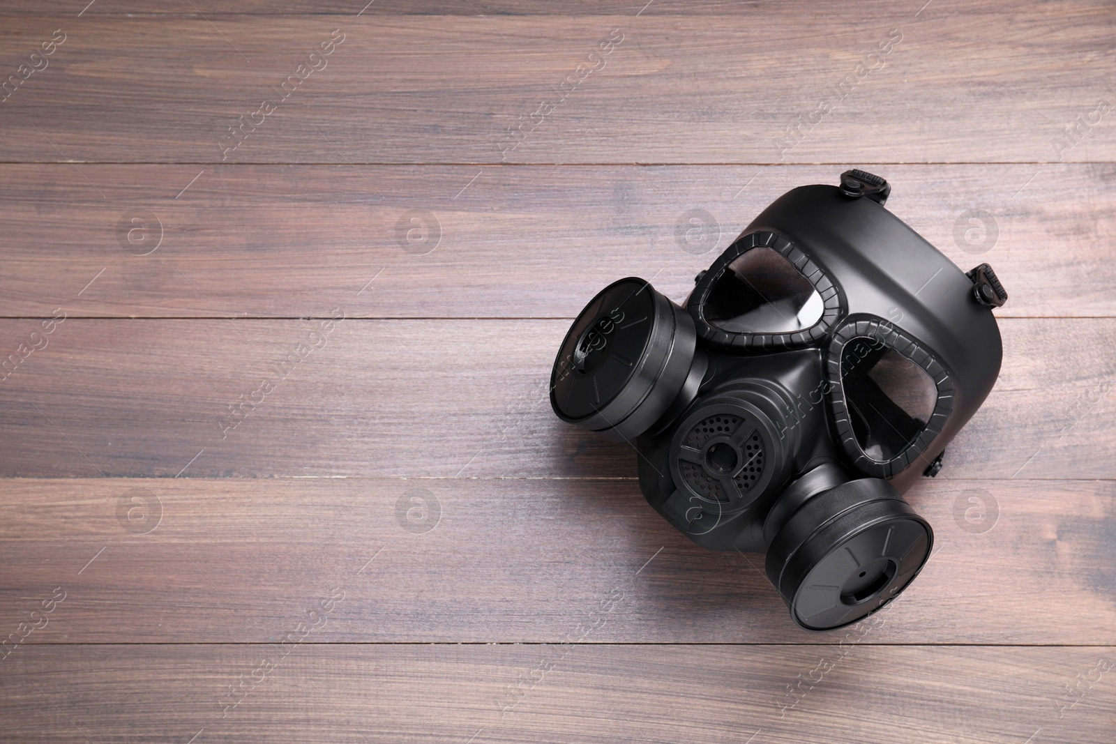 Photo of One gas mask on wooden background, top view. Space for text