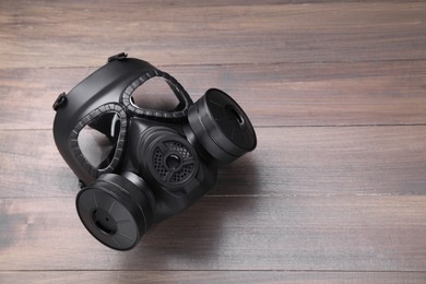 One gas mask on wooden background, top view. Space for text