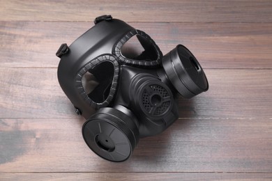 Photo of One gas mask on wooden background, top view