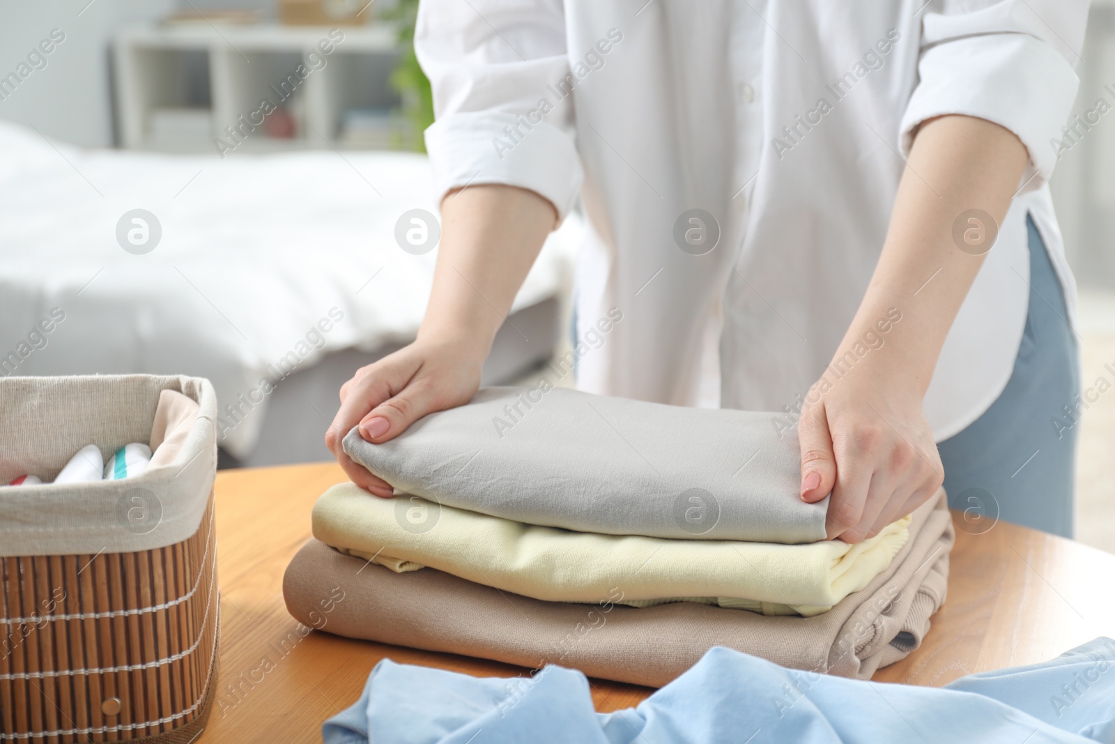 Photo of Woman folding clothes at wooden table indoors, closeup