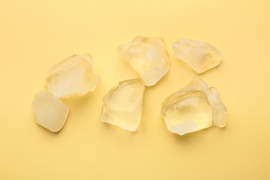Pieces of crushed ice on yellow background, top view