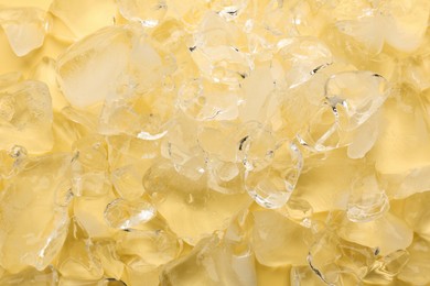 Pieces of crushed ice on yellow background, top view