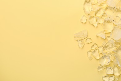 Photo of Pieces of crushed ice on yellow background, top view. Space for text