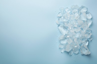 Photo of Pieces of crushed ice on light blue background, top view. Space for text