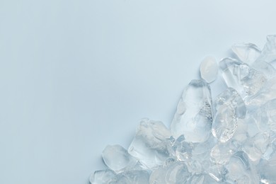 Pieces of crushed ice on light blue background, top view. Space for text