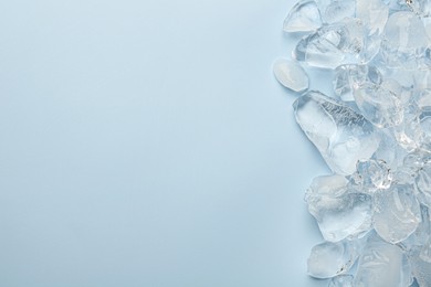 Photo of Pieces of crushed ice on light blue background, top view. Space for text