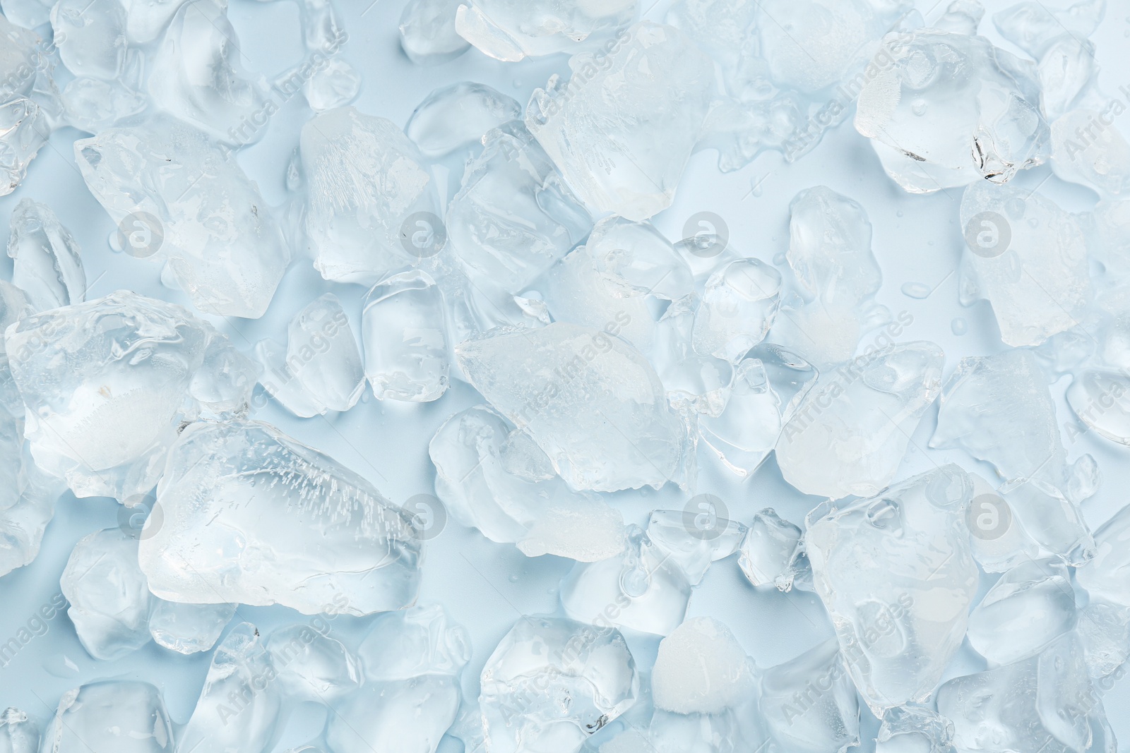 Photo of Pieces of crushed ice on light blue background, top view