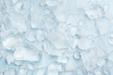 Pieces of crushed ice on light blue background, top view