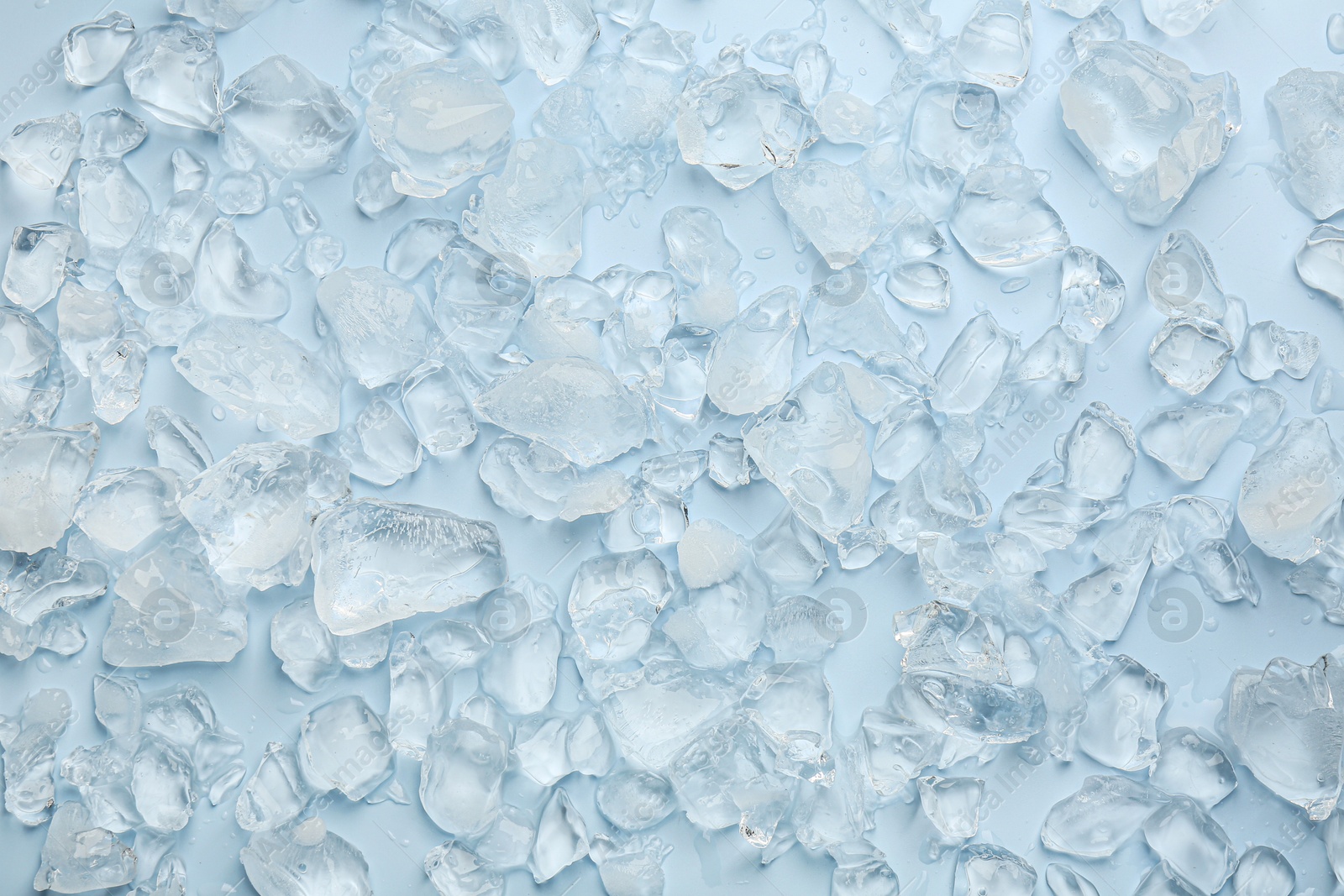 Photo of Pieces of crushed ice on light blue background, top view