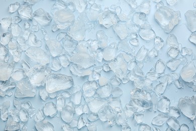 Pieces of crushed ice on light blue background, top view