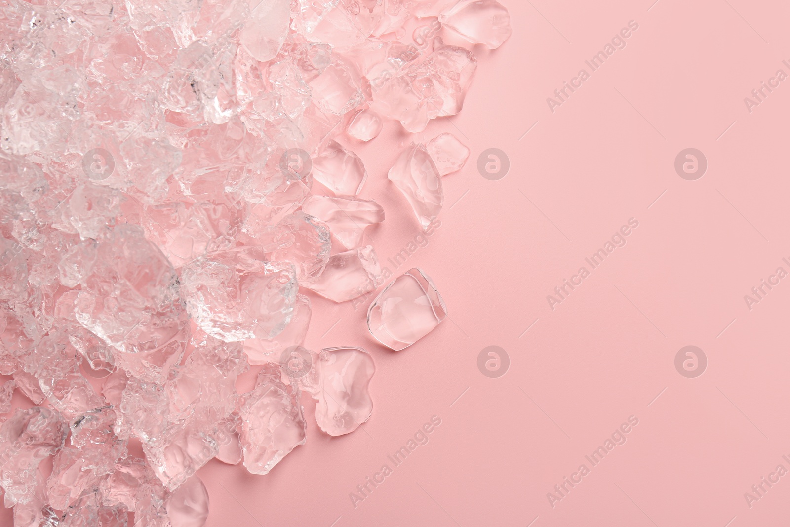 Photo of Pieces of crushed ice on pink background, top view. Space for text