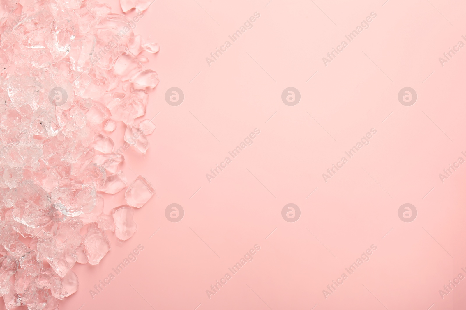 Photo of Pieces of crushed ice on pink background, top view. Space for text