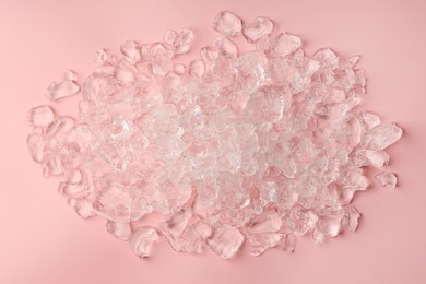 Pieces of crushed ice on pink background, top view