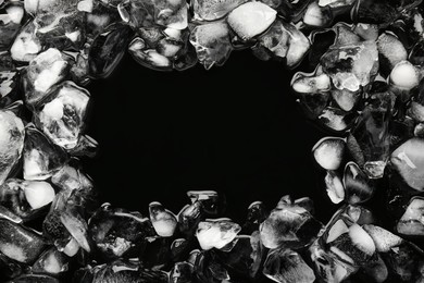 Frame of crushed ice on black background, top view. Space for text