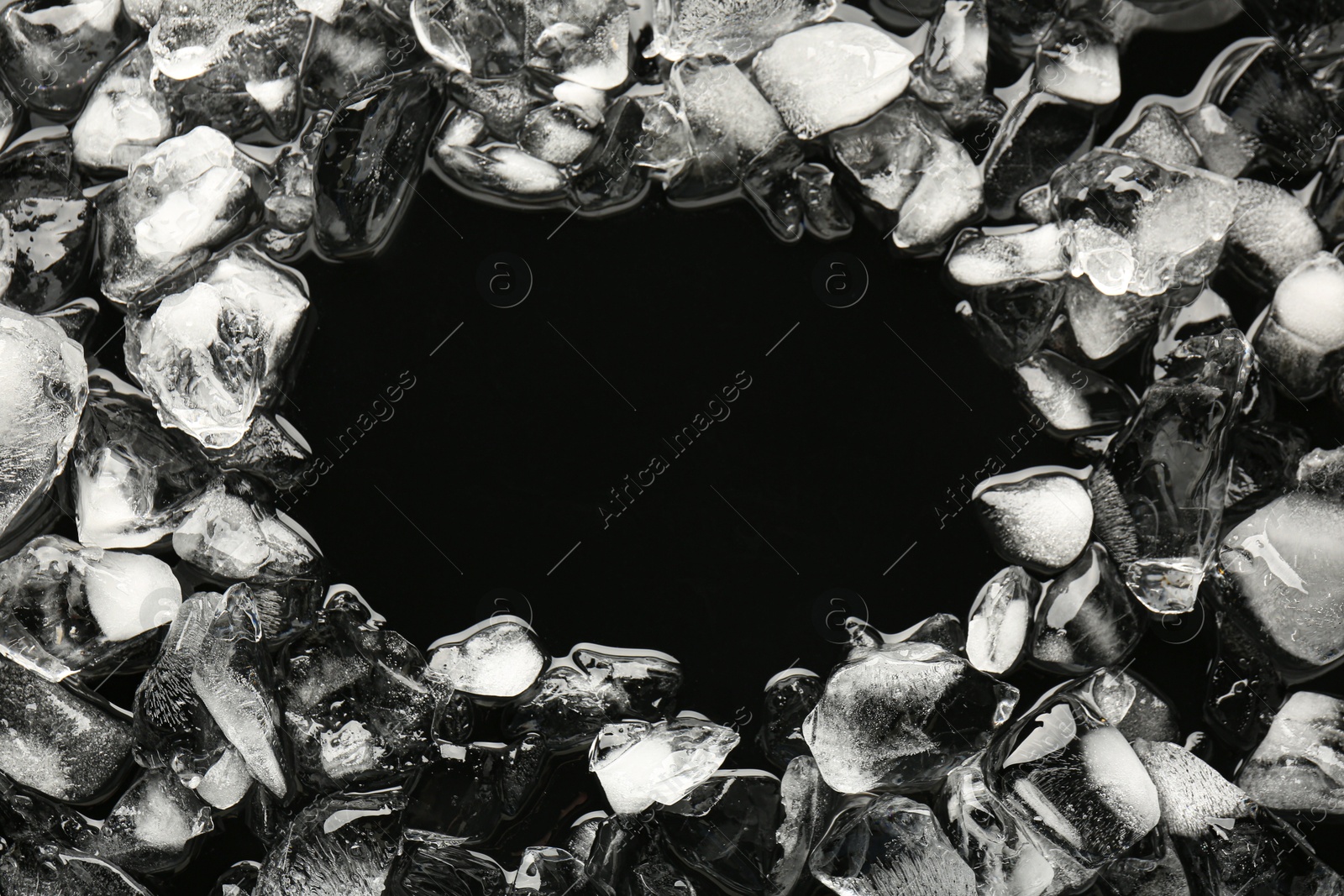 Photo of Frame of crushed ice on black background, above view. Space for text