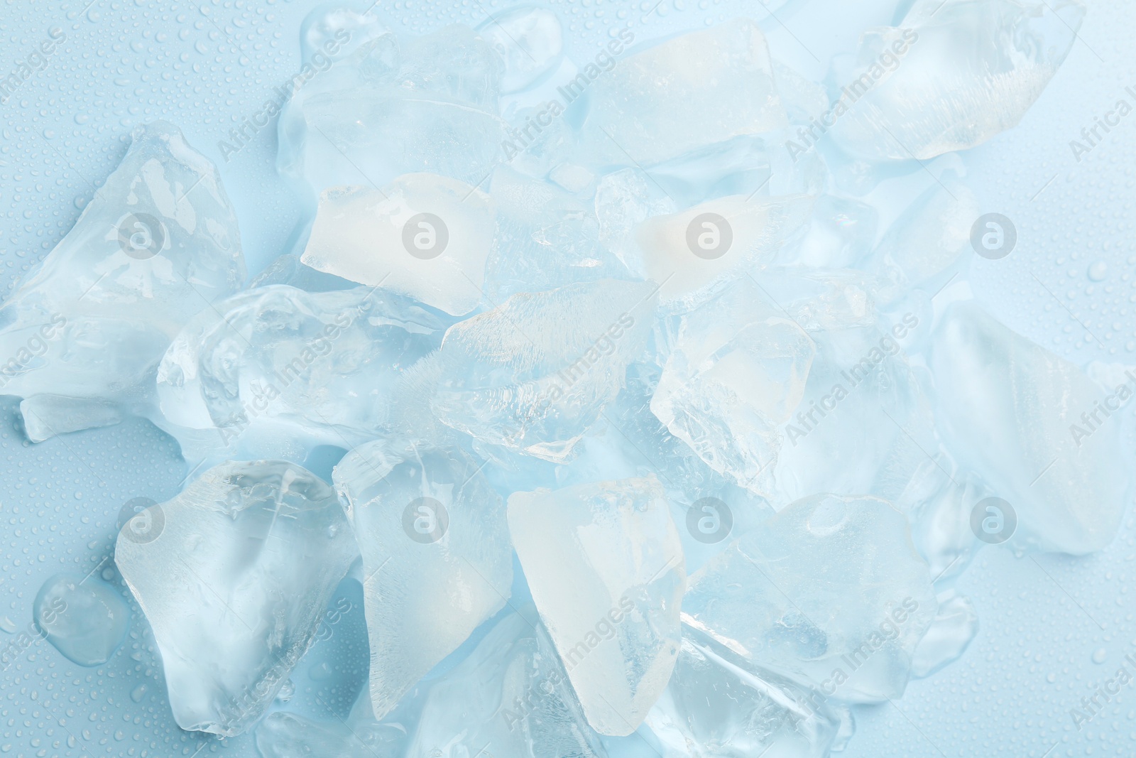 Photo of Pieces of crushed ice on light blue background