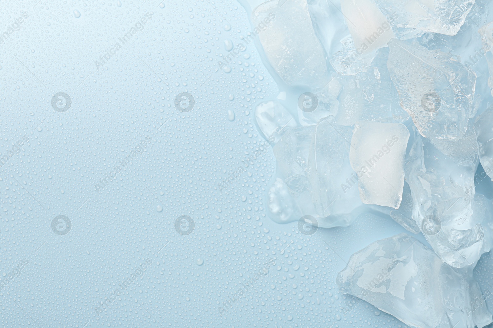 Photo of Pieces of crushed ice on light blue background, top view. Space for text