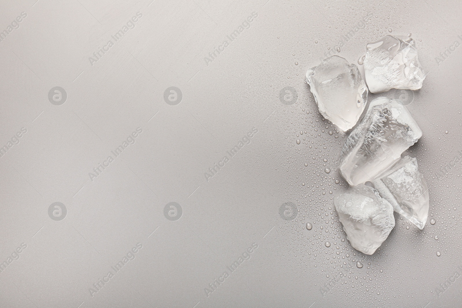 Photo of Pieces of crushed ice on grey background, top view. Space for text