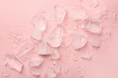 Pieces of crushed ice on pink background, top view