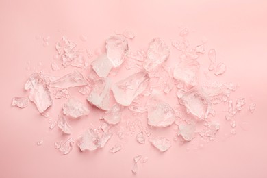 Pieces of crushed ice on pink background, top view