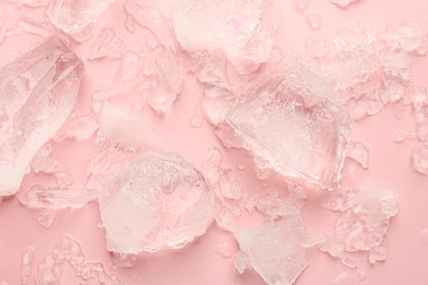 Pieces of crushed ice on pink background, top view