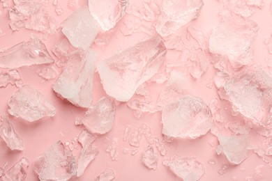 Pieces of crushed ice on pink background, top view