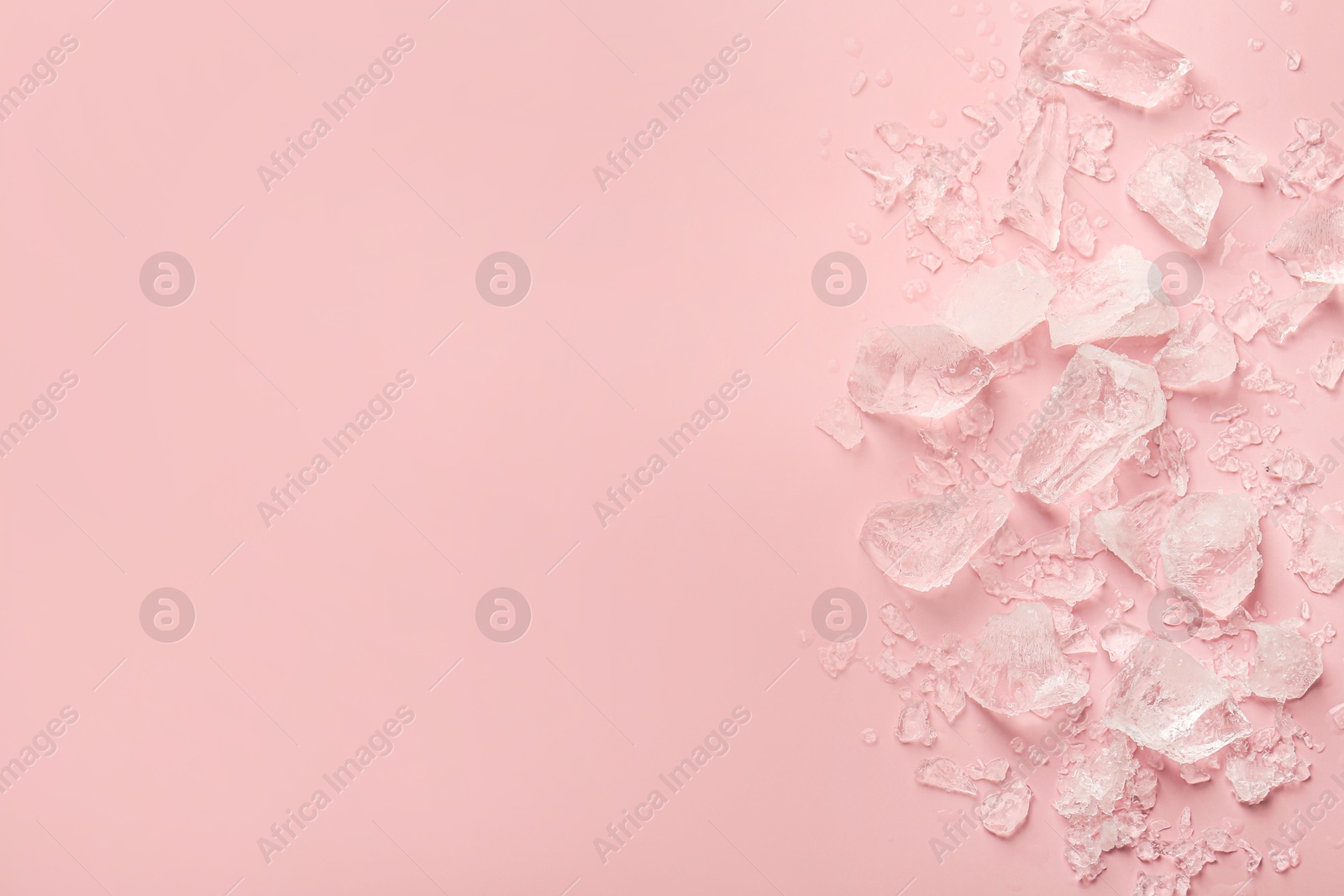 Photo of Pieces of crushed ice on pink background, top view. Space for text