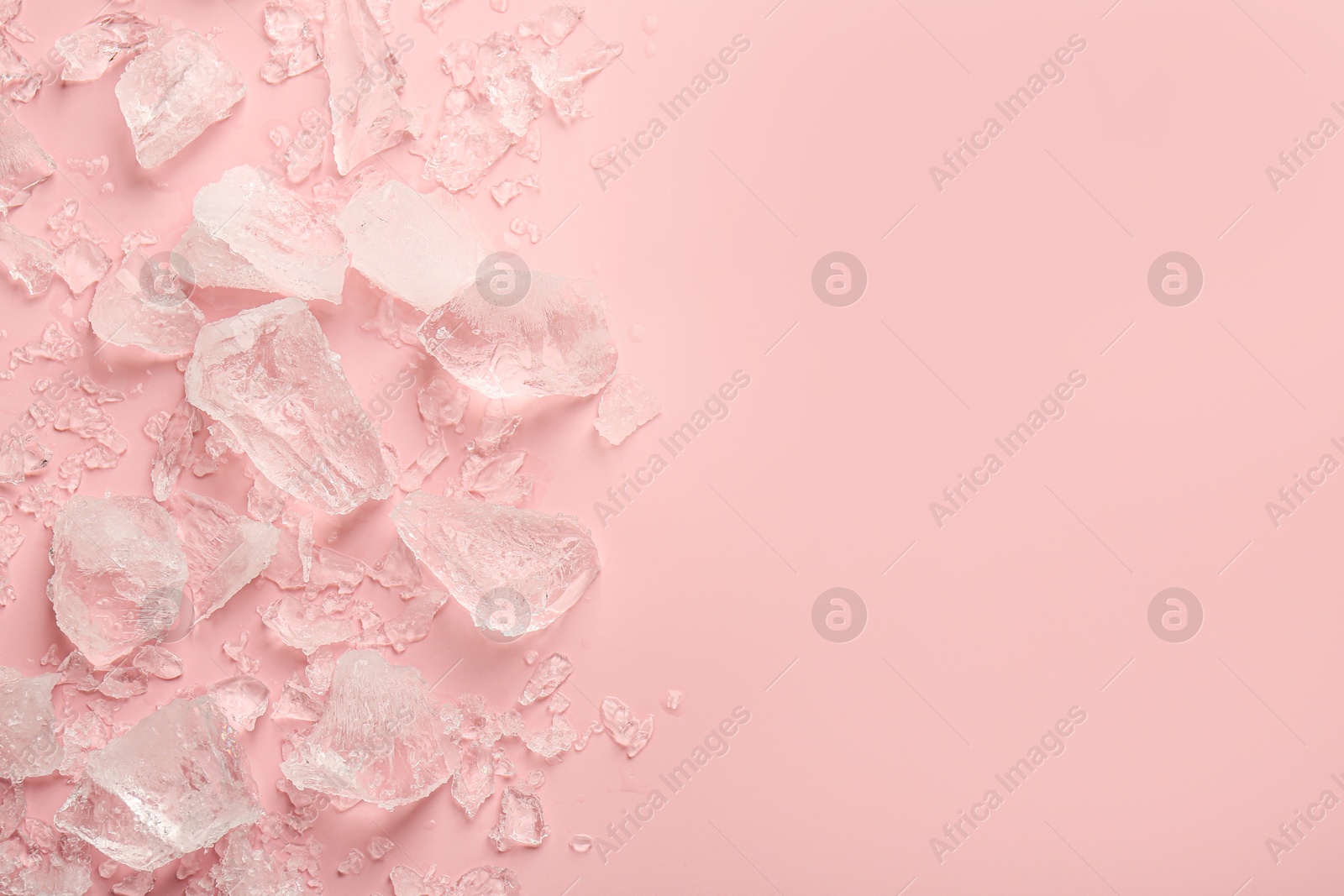 Photo of Pieces of crushed ice on pink background, top view. Space for text