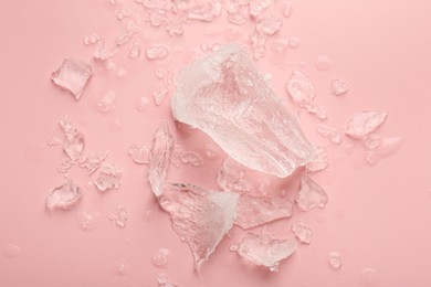 Pieces of crushed ice on pink background, top view