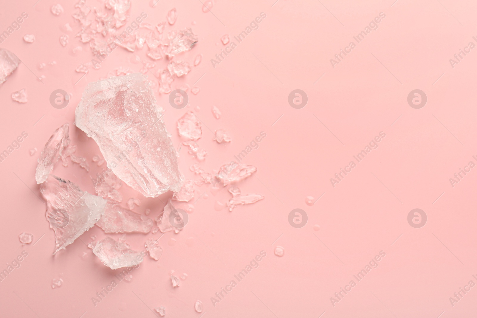 Photo of Pieces of crushed ice on pink background, top view. Space for text