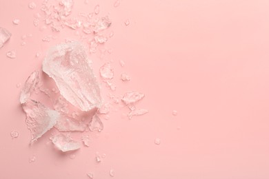 Pieces of crushed ice on pink background, top view. Space for text