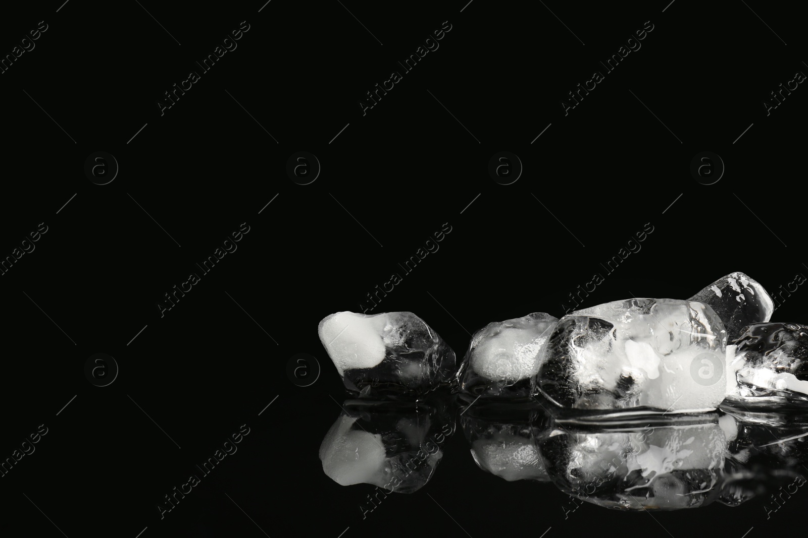 Photo of Pile of crushed ice on black mirror surface, space for text