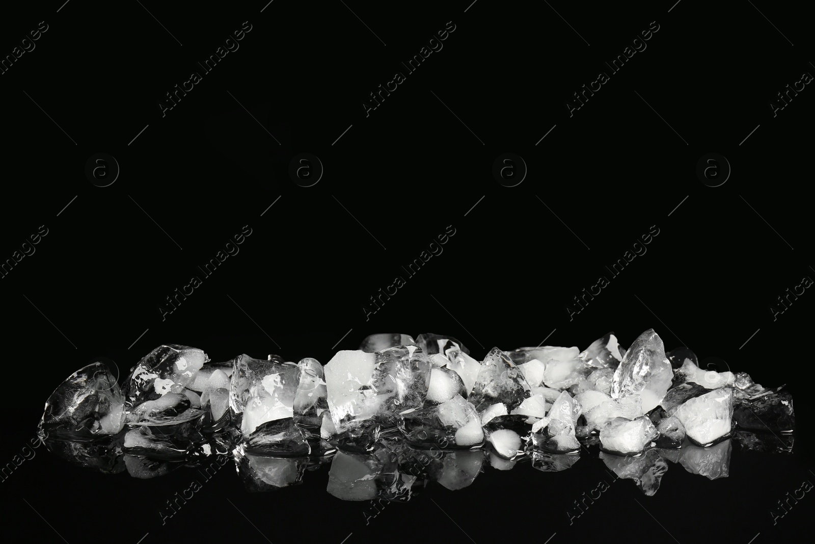 Photo of Pile of crushed ice on black mirror surface, space for text