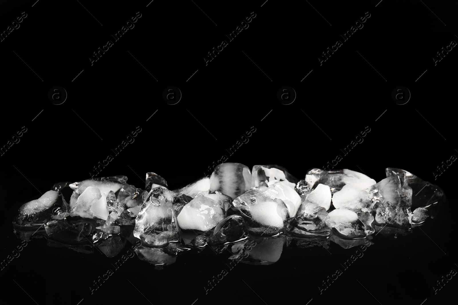 Photo of Pile of crushed ice on black mirror surface, space for text