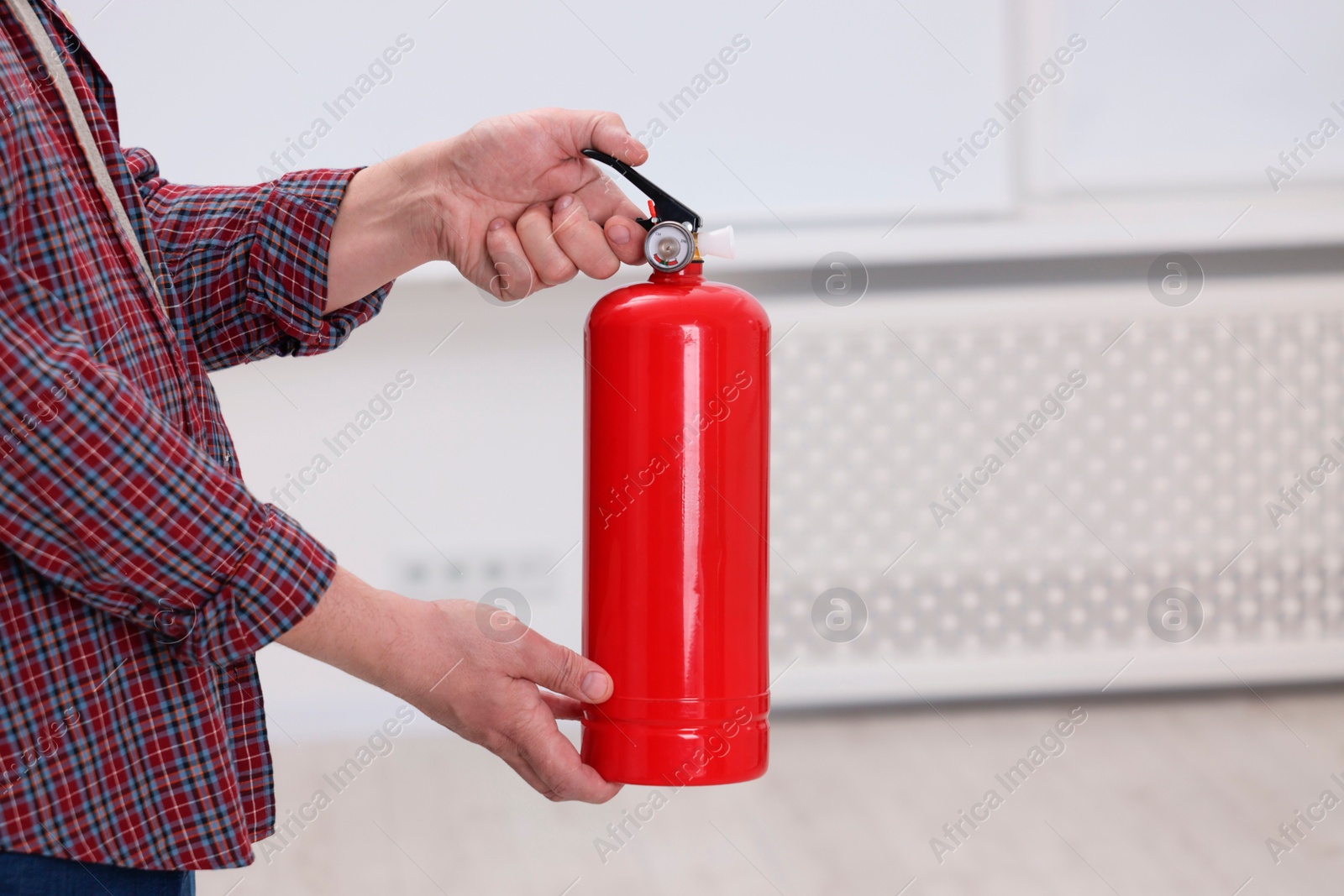 Photo of Man with fire extinguisher indoors, closeup. Space for text