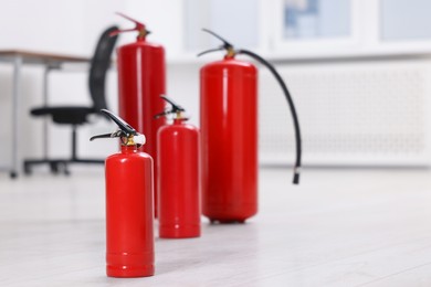 Photo of Fire extinguishers on floor indoors, space for text