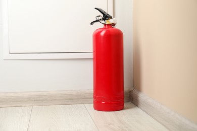 Photo of Fire extinguisher on floor indoors. Safety equipment