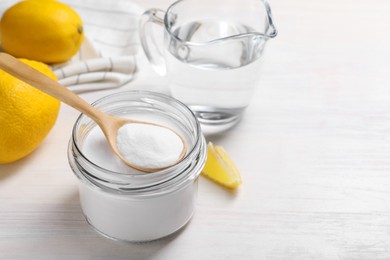 Baking soda, vinegar and lemons on white wooden table, space for text