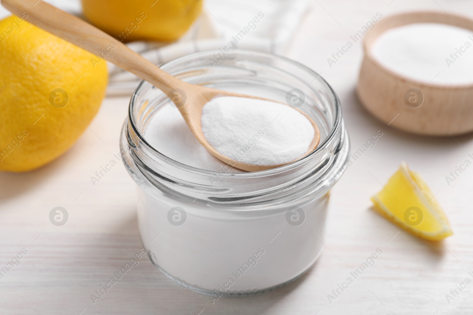Photo of Baking soda and lemons on white wooden table, closeup
