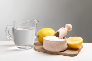 Baking soda, vinegar and lemons on white wooden table