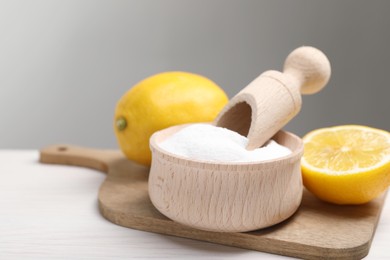 Baking soda and lemons on white wooden table, closeup