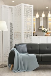 Stylish room interior with lamp, sofa and folding screen
