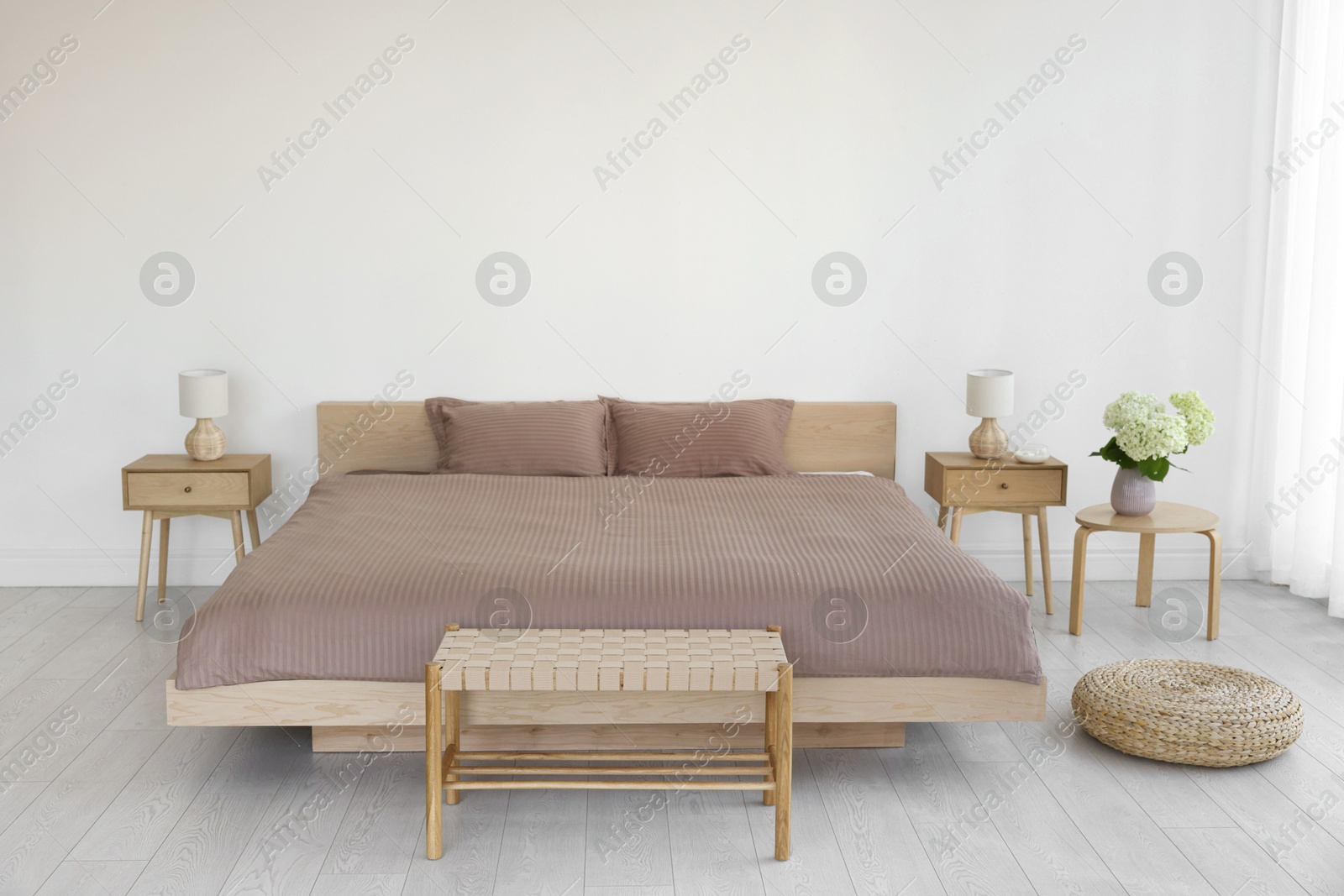 Photo of Stylish bedroom interior with large bed, ottoman and bedside tables