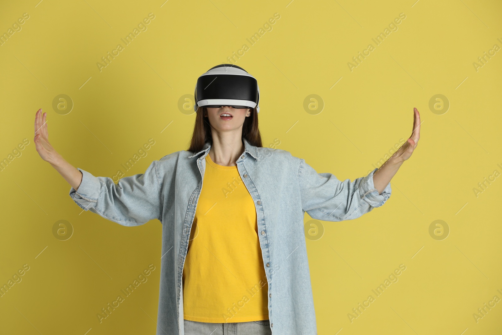 Photo of Woman using virtual reality headset on yellow background