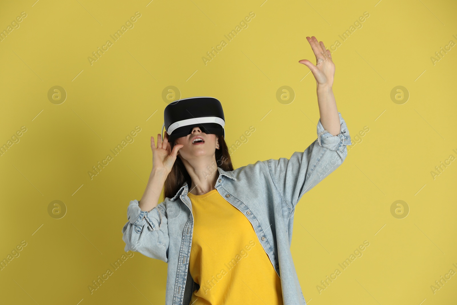 Photo of Woman using virtual reality headset on yellow background