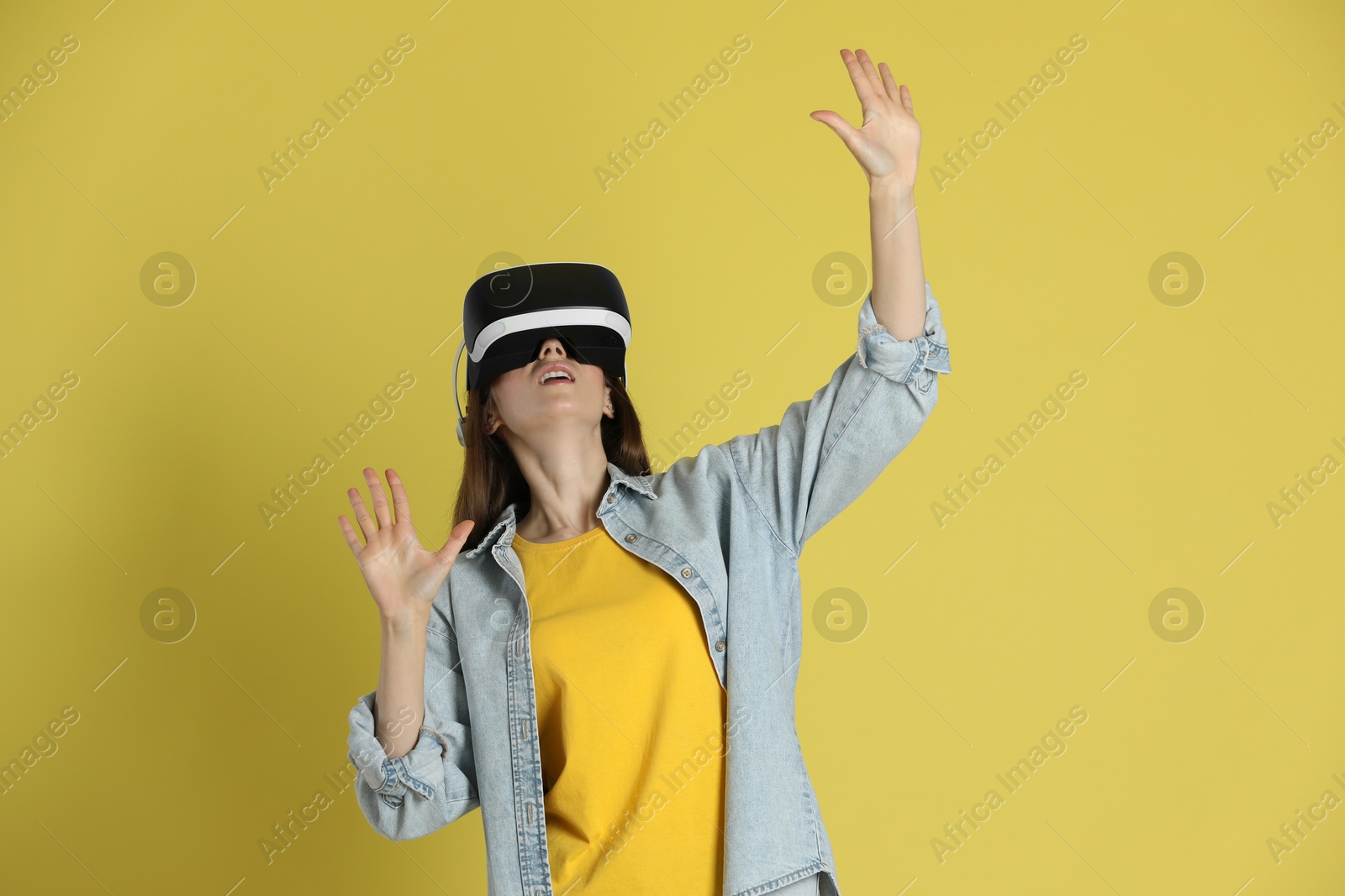 Photo of Woman using virtual reality headset on yellow background