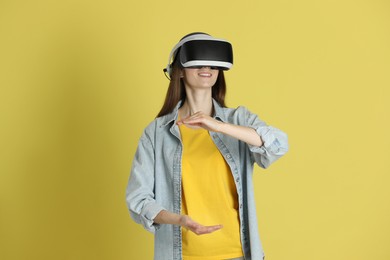 Smiling woman using virtual reality headset on yellow background