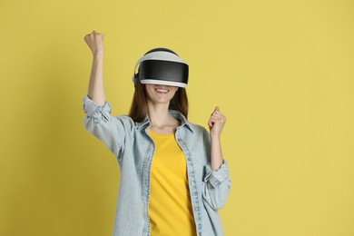 Smiling woman using virtual reality headset on yellow background